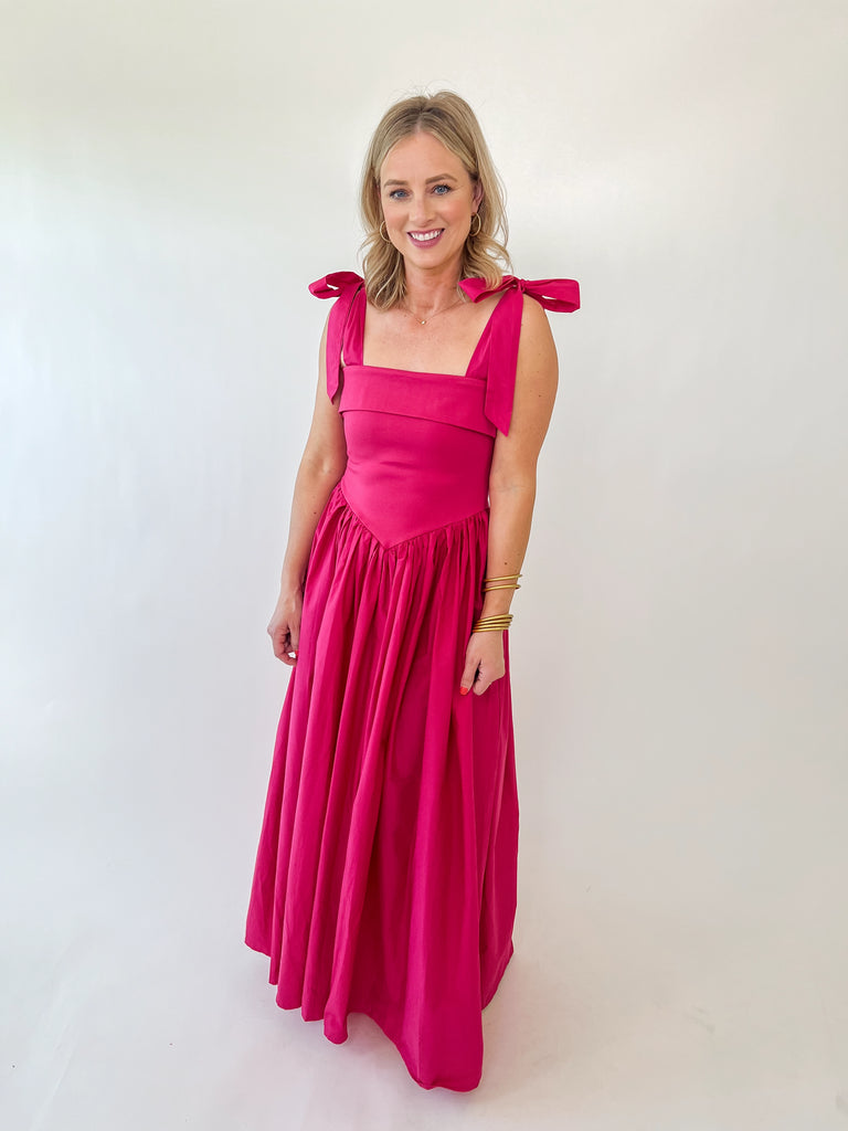 Woman wearing The Whitney Dress – hot pink satin maxi with shoulder bows