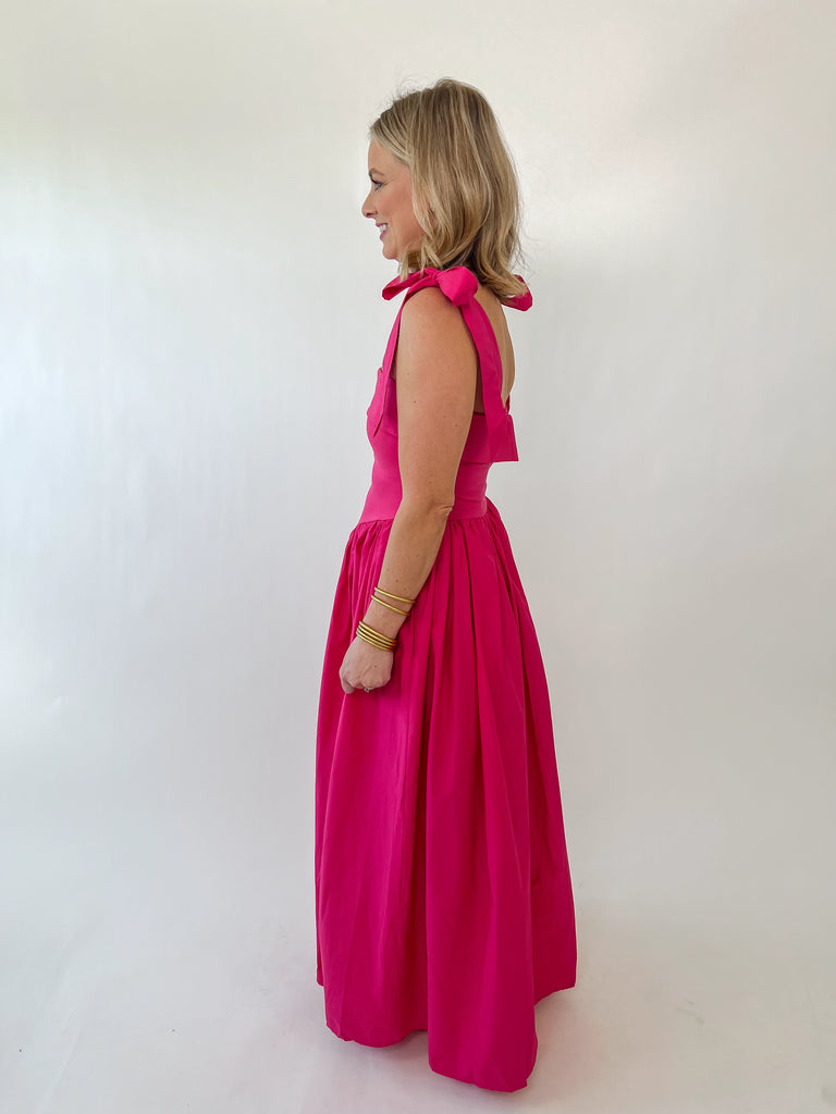 Woman wearing The Whitney Dress – hot pink satin maxi with shoulder bows