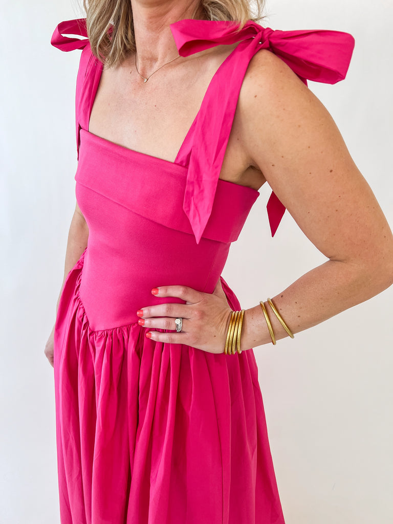 Woman wearing The Whitney Dress – hot pink satin maxi with shoulder bows