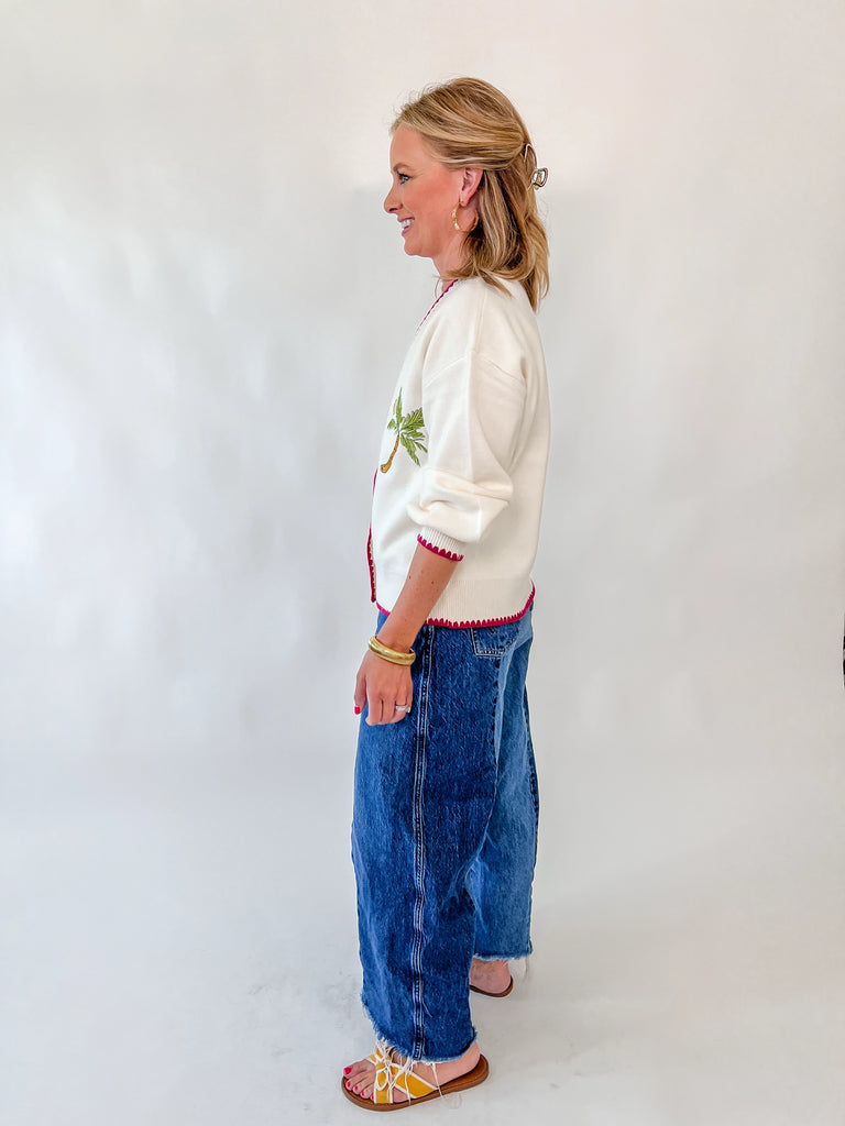 Woman wearing cream cardigan with fruit embroidery and pink trim