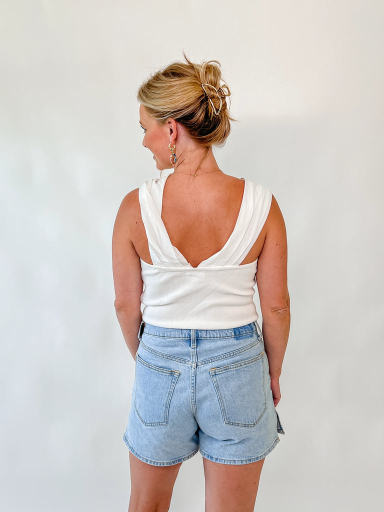 Woman wearing ivory twist-front sleeveless bodysuit with crossover straps