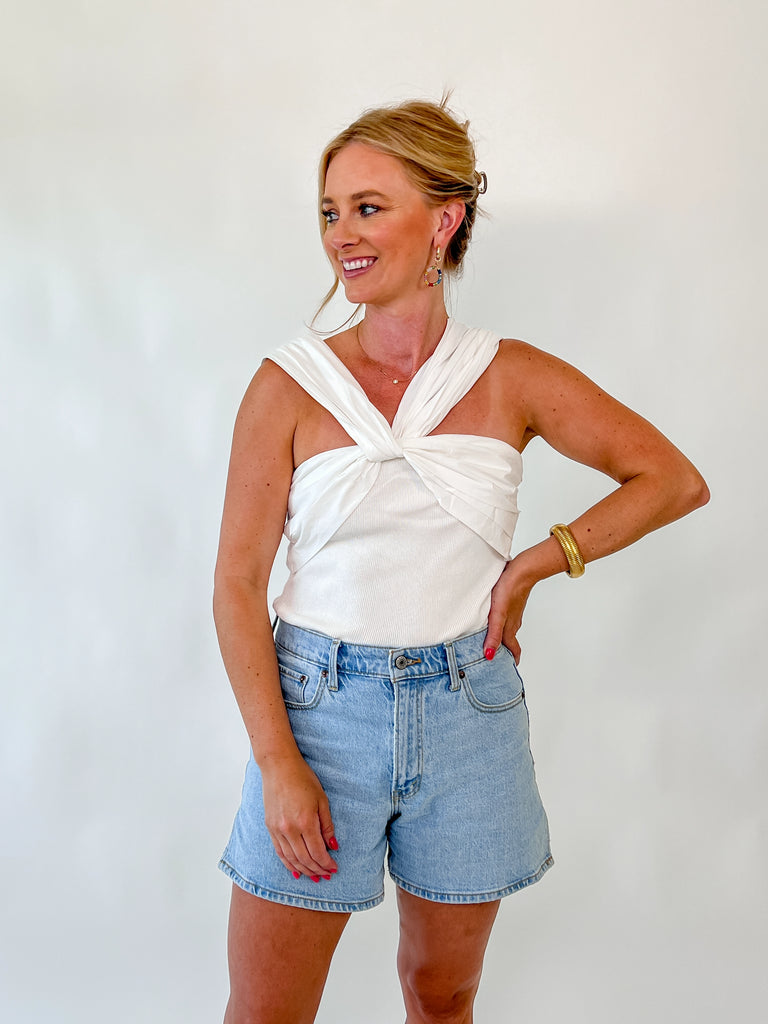 Woman wearing ivory twist-front sleeveless bodysuit with crossover straps