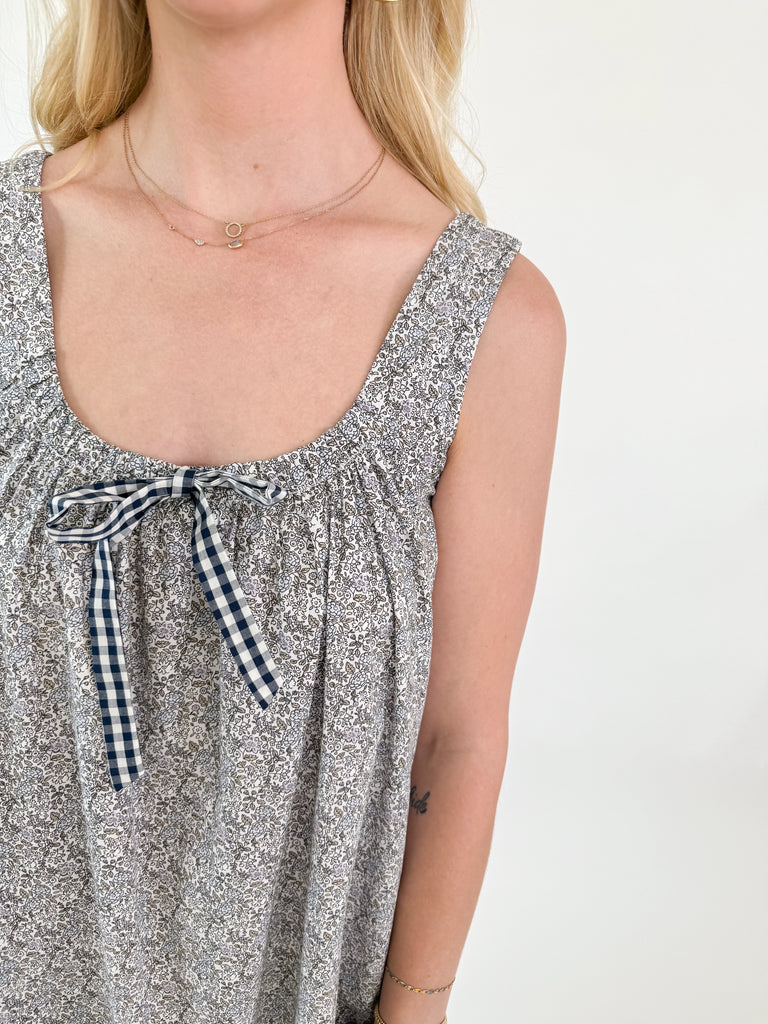 Girl wearing a grey floral midi with tie neckline, wide straps, and side pockets